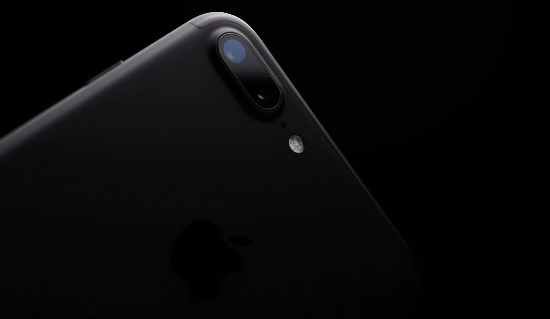 Close-up of a black smartphone camera and flash module on a dark background.