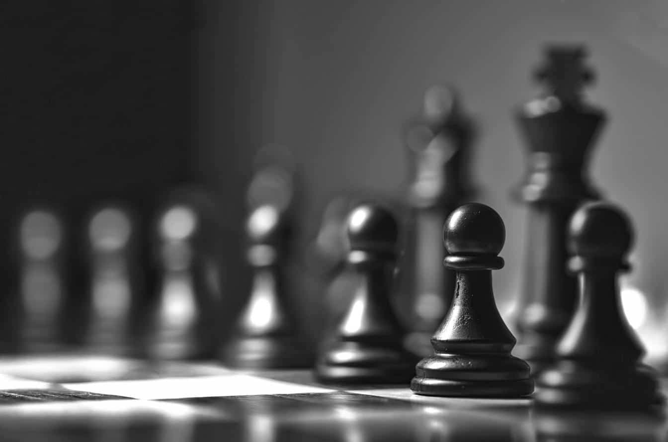 Close-up of black chess pawns and king pieces on a chessboard symbolising strategic planning.