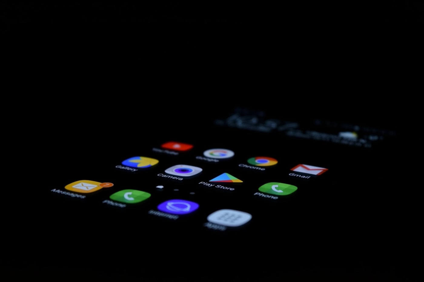Smartphone screen displaying app icons including Messages, Camera, Play Store, Chrome, Gmail, and Phone in a dark environment.