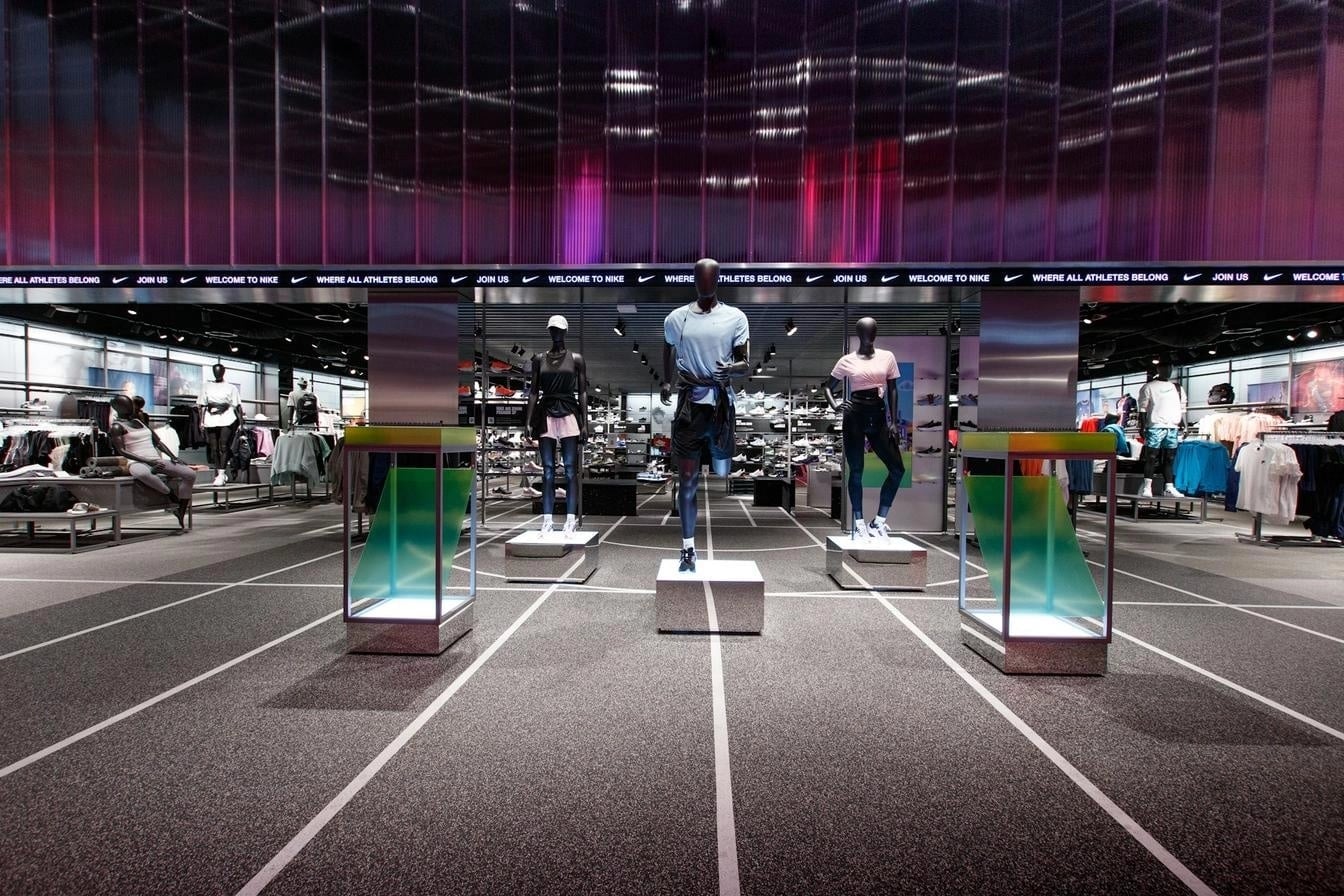 Interior view of a retail sportswear store with mannequins and product displays under LED lighting.