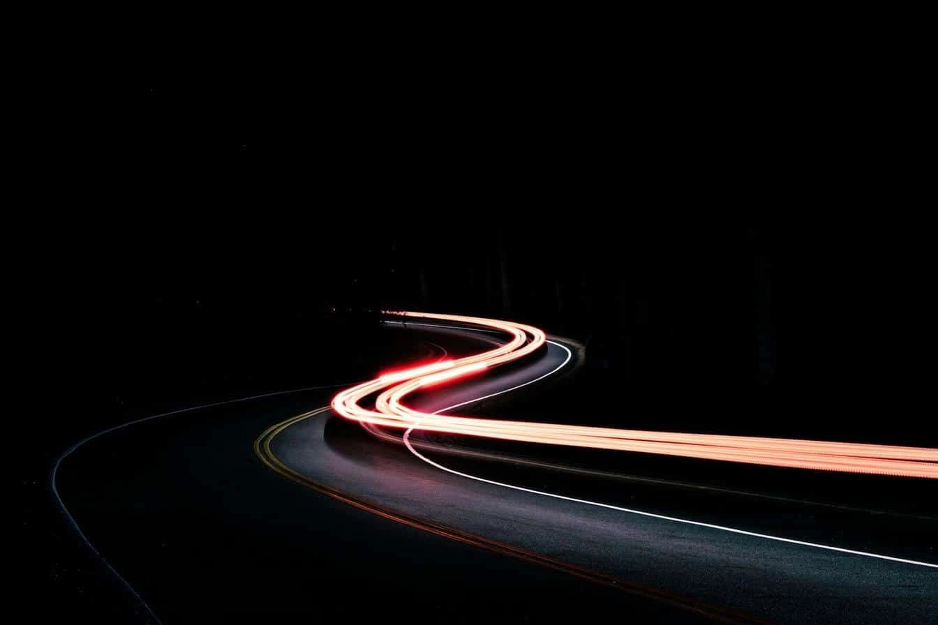 Curved road with red and white light trails representing speed, innovation, and forward momentum.