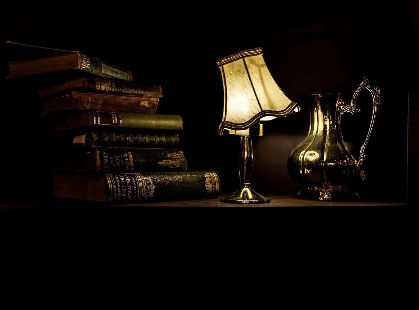 Stack of antique books with a brass lamp and jug symbolising research, learning, and insight.