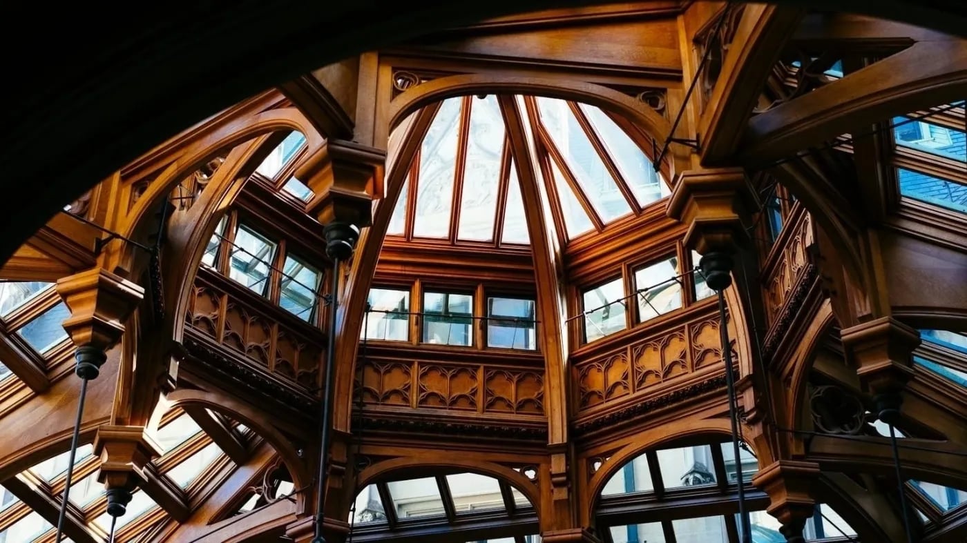 Intricate wooden and glass vaulted ceiling with gothic-style arches and natural light.