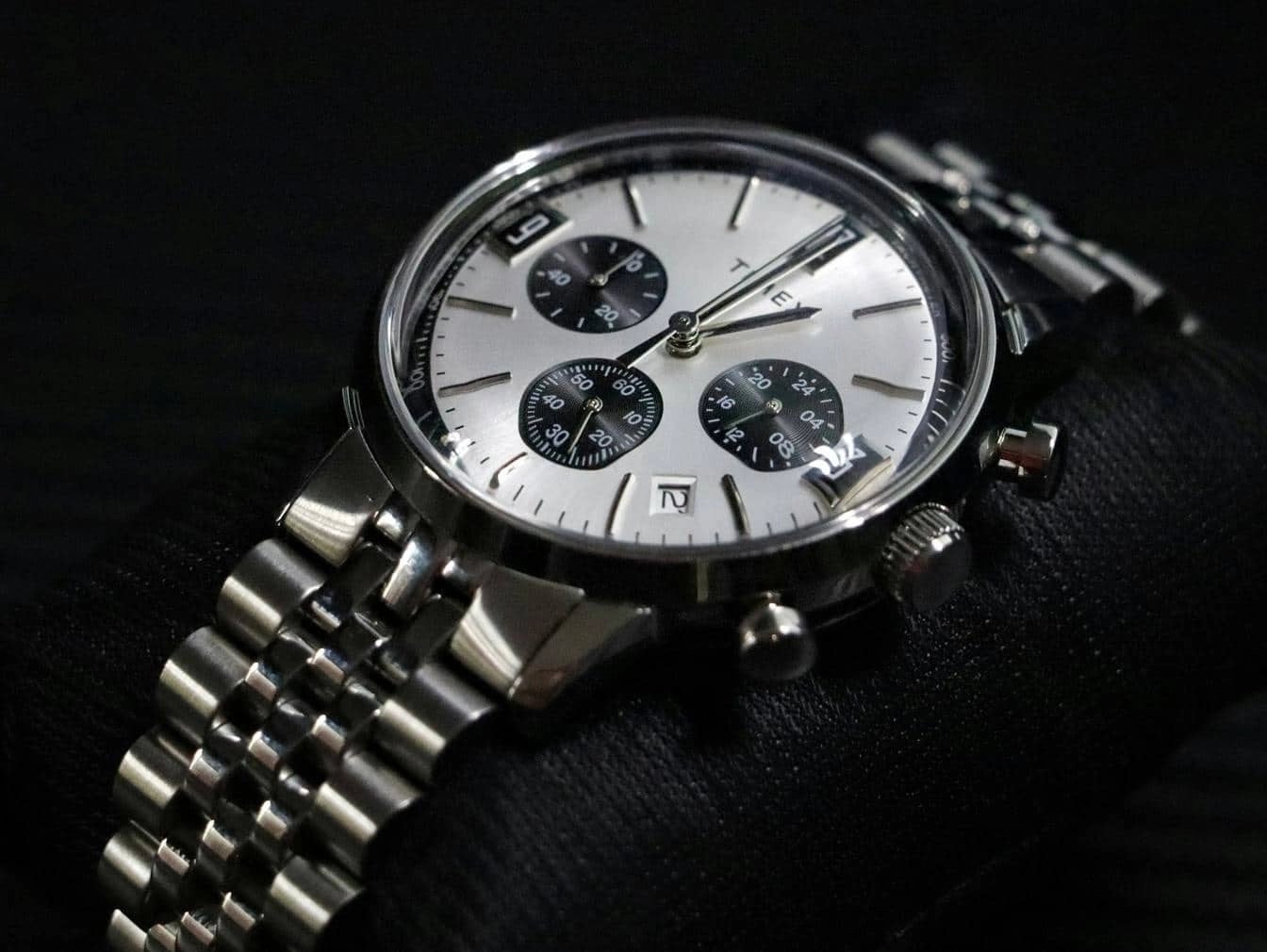 Stainless steel chronograph watch with silver dial and subdials on black cushion.