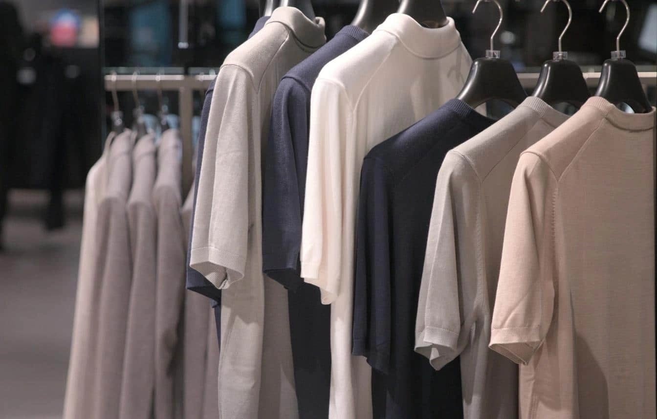 Assorted neutral-toned shirts on hangers representing local retail presentation and visual merchandising.