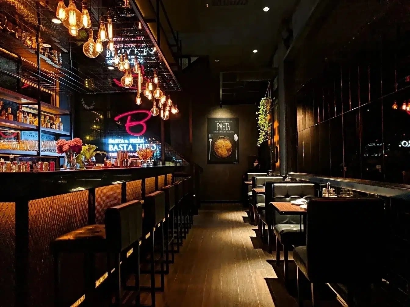A stylish restaurant and bar with warm ambient lighting, leather seating, and a well-stocked bar, creating a cozy and elegant dining atmosphere.