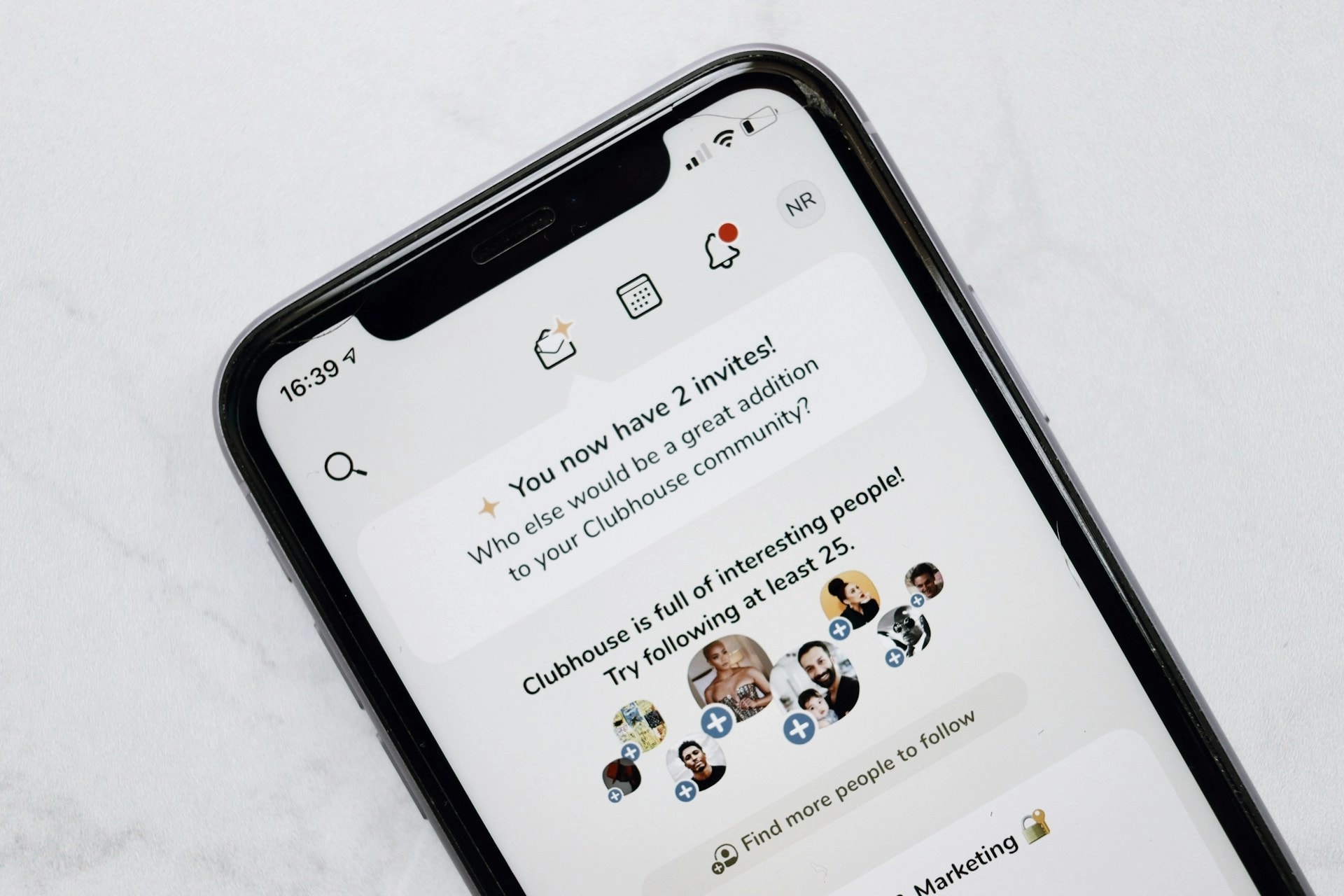 Smartphone displaying the Clubhouse app interface with user invitations and recommended people to follow.