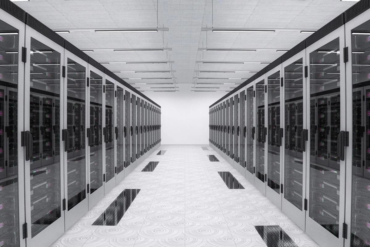 Long corridor inside a modern data center lined with rows of glass-fronted server racks on both sides, representing large-scale digital infrastructure.