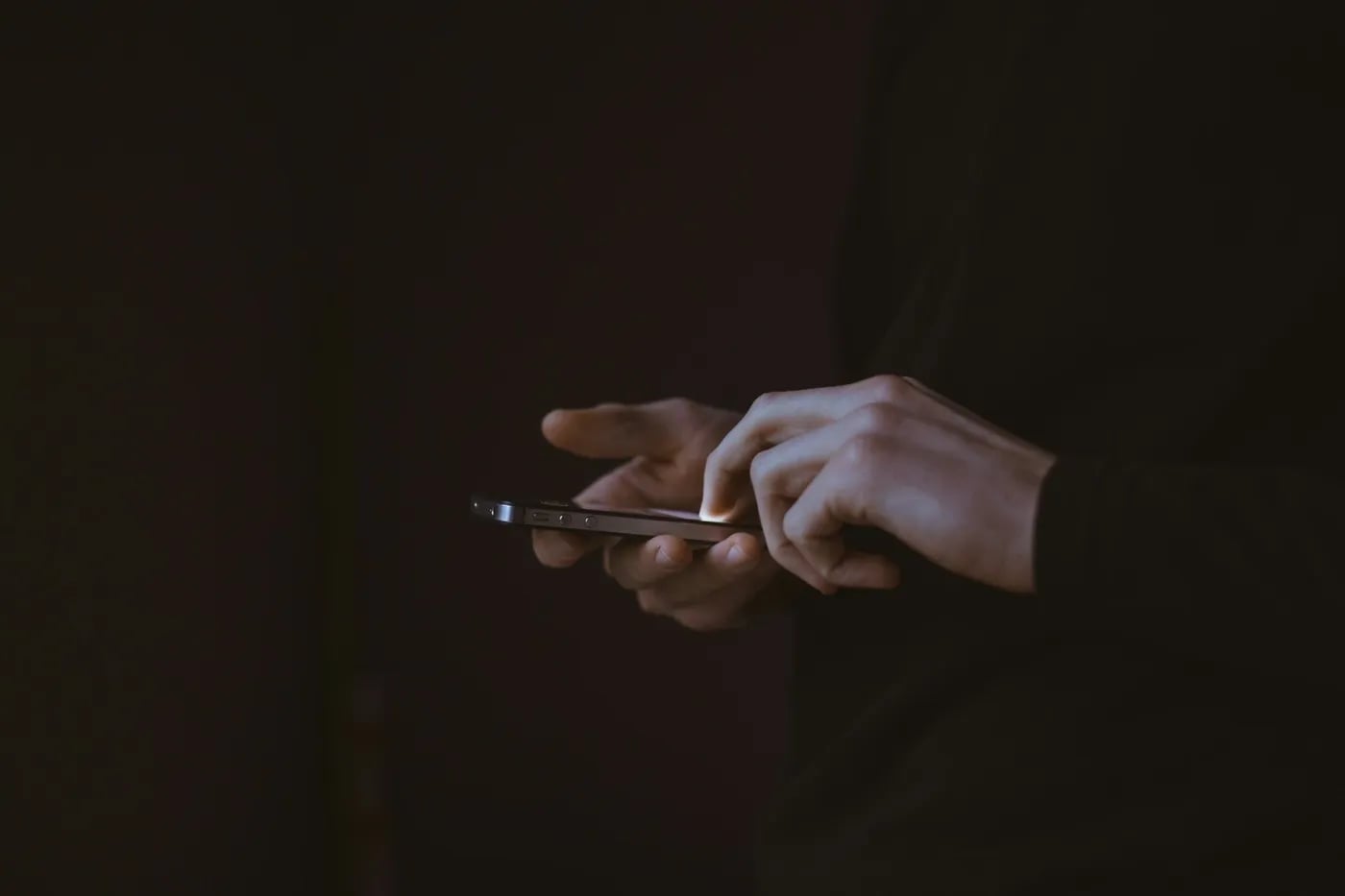Person using a smartphone in a dimly lit environment.