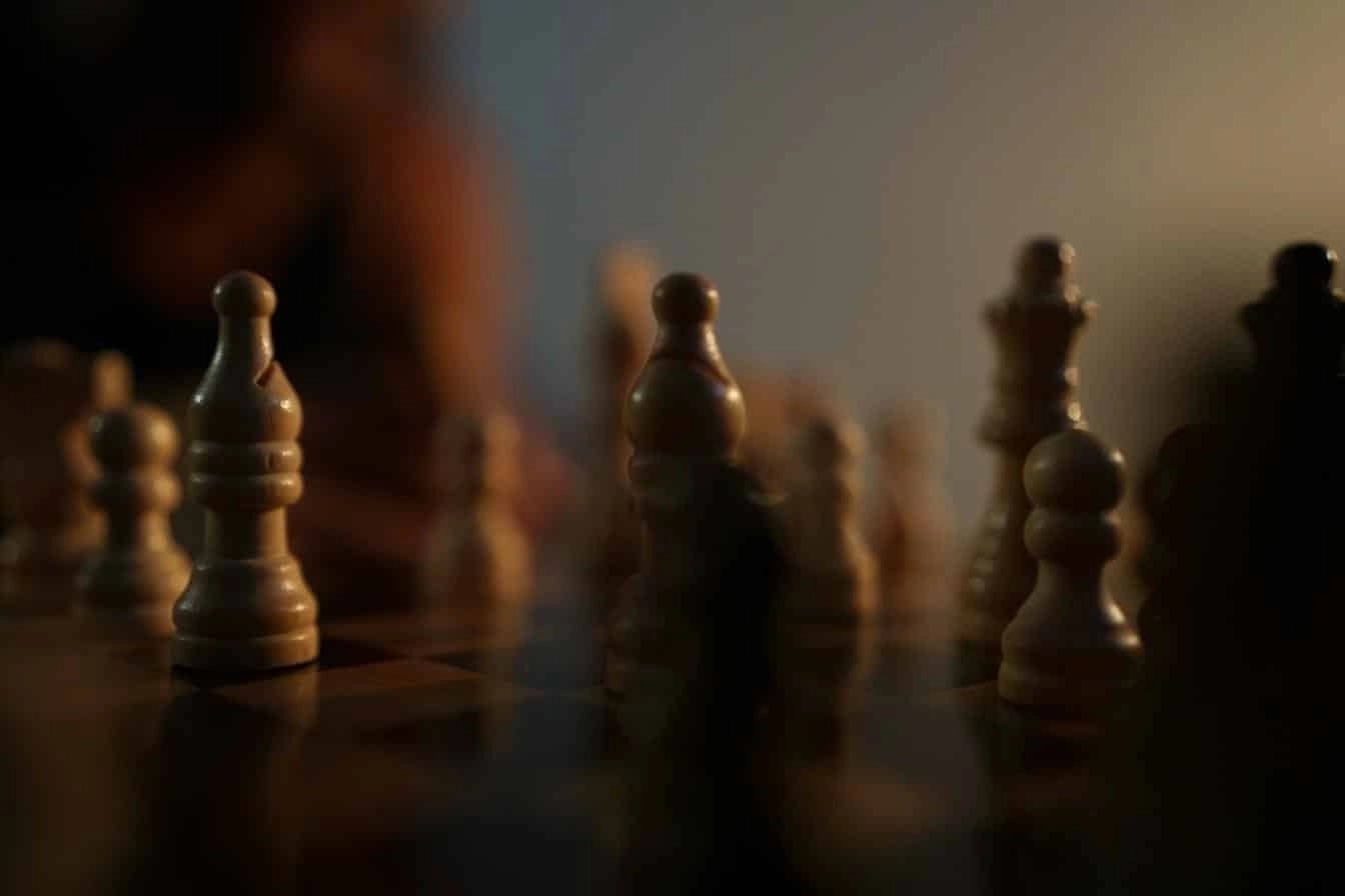 Close-up of a chess board with wooden pieces under moody lighting, symbolizing strategy and planning.